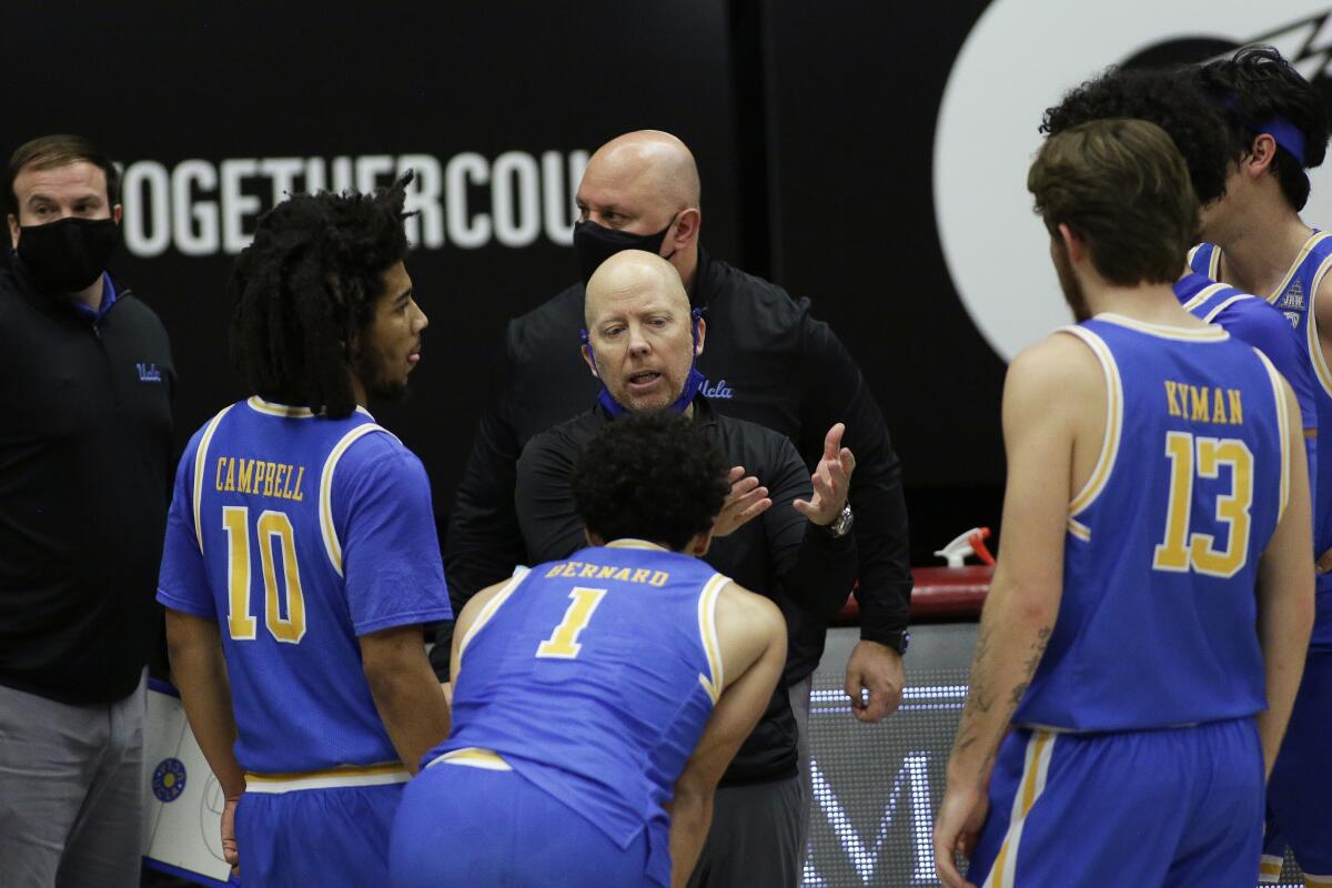 Coach Mick Cronin talks to UCLA players on the sideline.