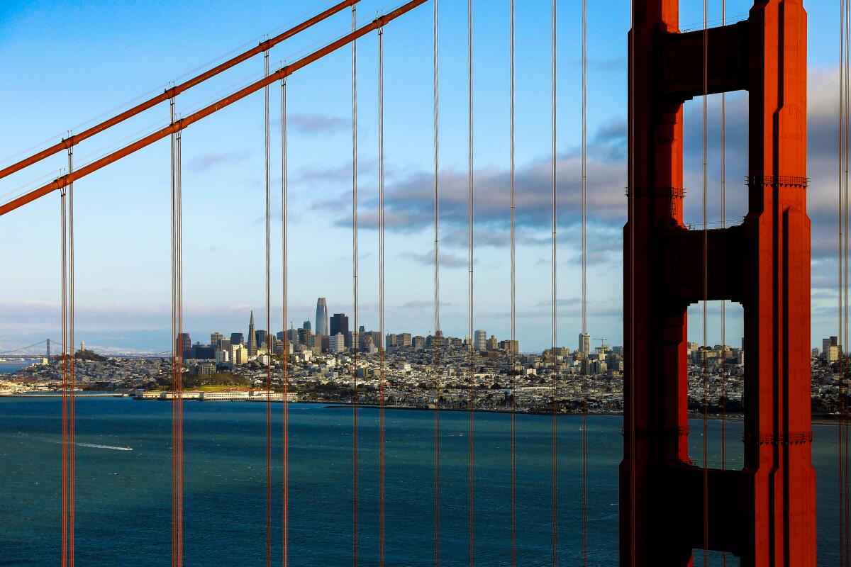 L'horizon du centre-ville de San Francisco est visible à travers les câbles qui soutiennent le Golden Gate Bridge par une journée ensoleillée