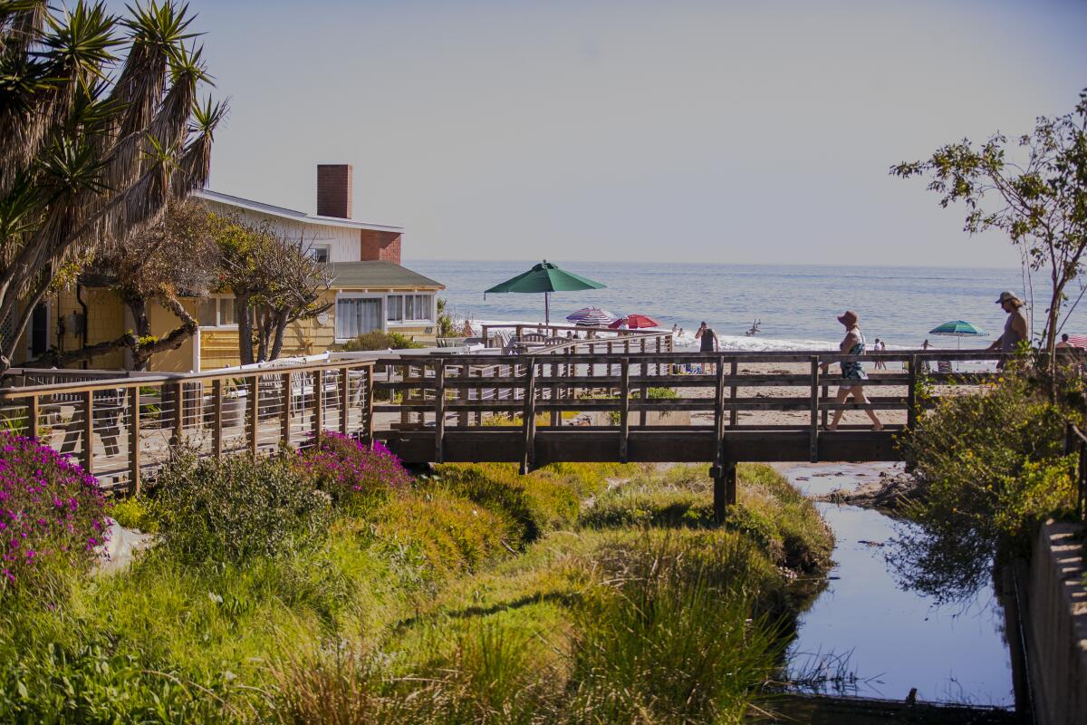 Beachgoers walk across a bridge at the Crystal Cove Historical District, built as a seaside colony between 1920 and 1940.