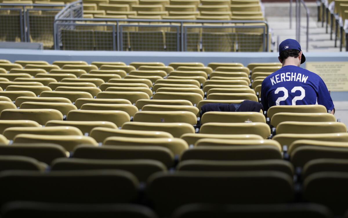 A fan wearing a t-shirt bearing the name of Dodgers ace Clayton Kershaw sits in the field-level seats at Dodger Stadium before the team's home opener against the San Francisco Giants. Some fans upset by the Dodgers' ongoing television debacle have threatened to boycott the team.