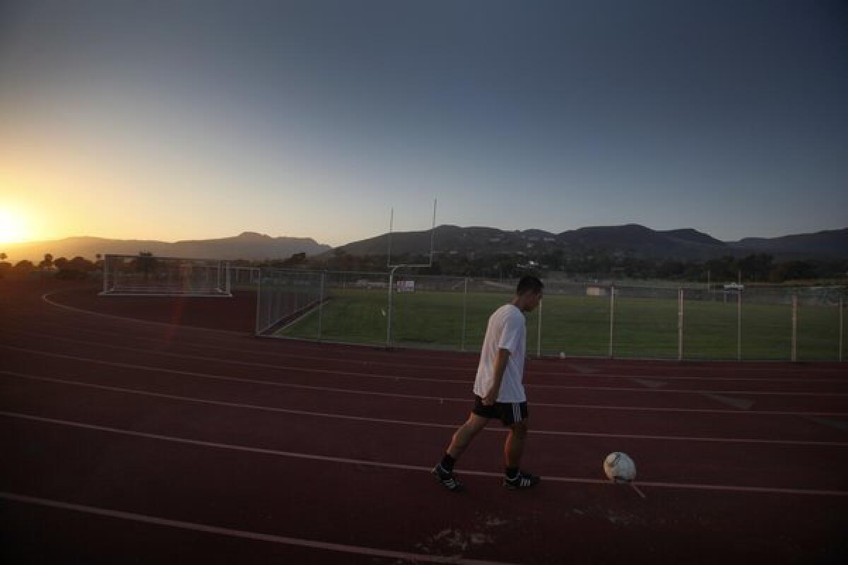 Kenan Jiang, 22, of Malibu, kicks a soccer ball while running at the Malibu High School track. Some classrooms inside a building on the adjacent middle school campus are being relocated because of concerns over possible toxins.