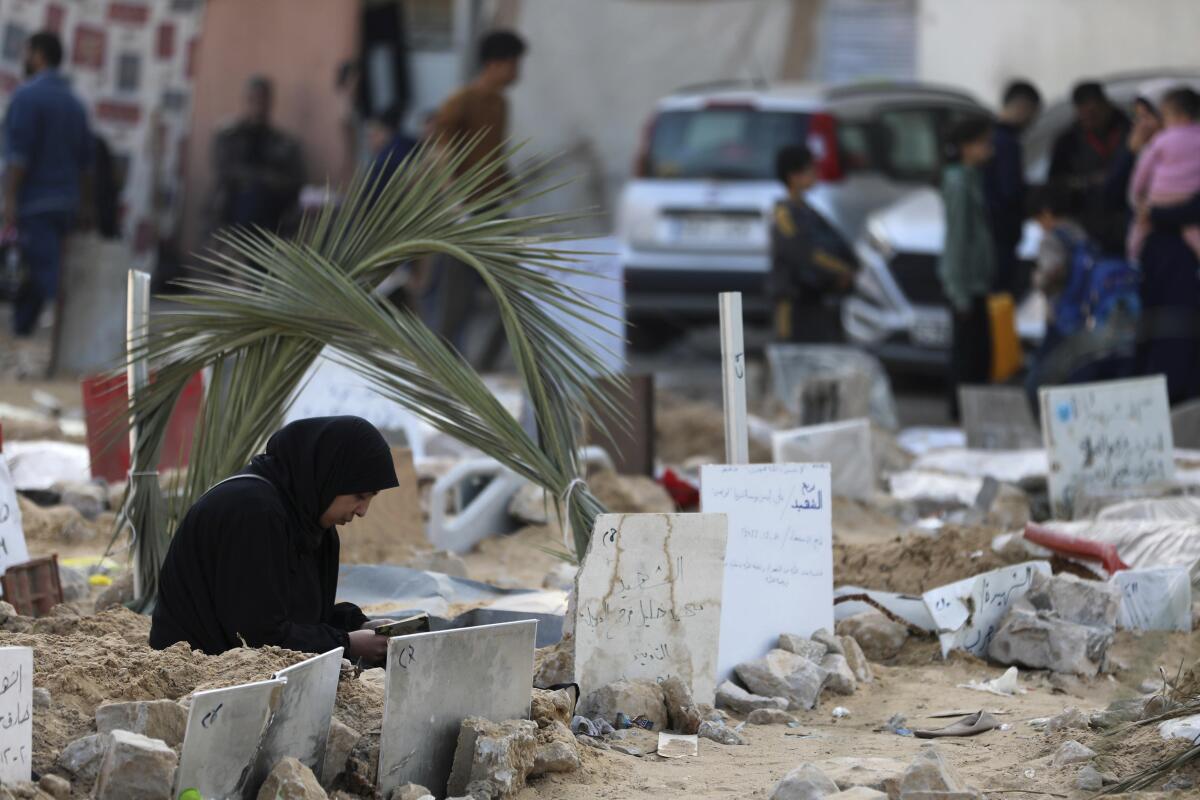 A person kneels by a grave in Gaza.