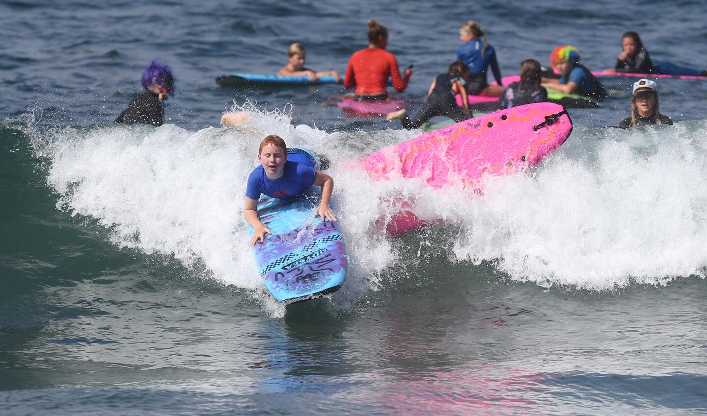 Participants frolic in the surf at the Laguna Beach Surf School summer program in Laguna Beach on Friday.