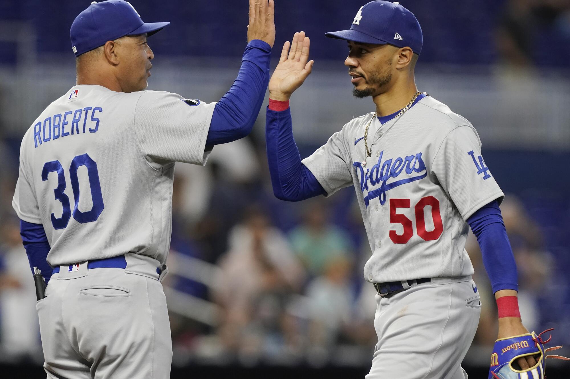 Dodgers manager Dave Roberts, left, congratulates right fielder Mookie Betts after the Dodgers' 8-1 win.
