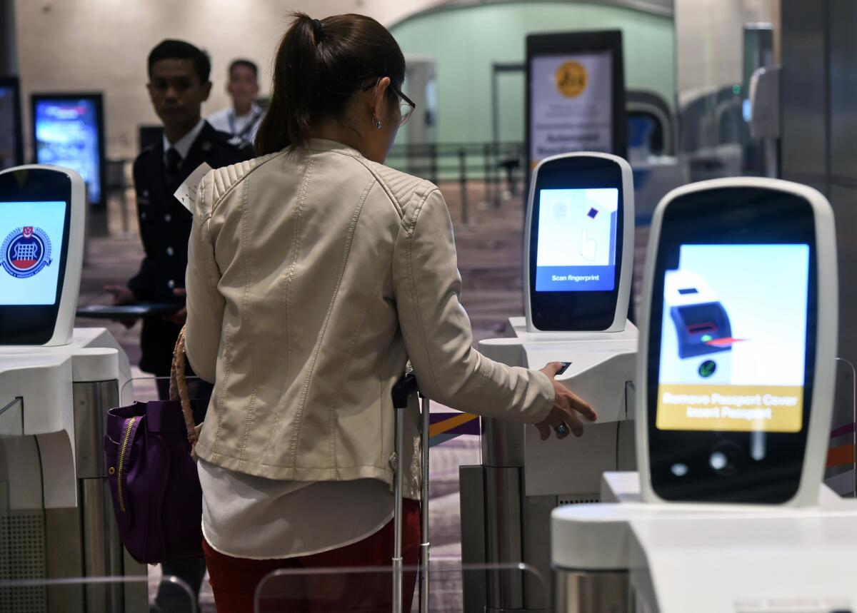 A passenger scans her thumb on an automated immigration gate at the newly opened Changi International Airport's Terminal 4 in Singapore.