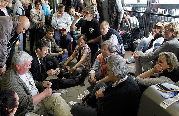 Stranded French tourists play cards and wait on the floor near the Air France ticket counter at LAX in hopes of getting on one of the four Air France flights departing for Paris on Tuesday.
