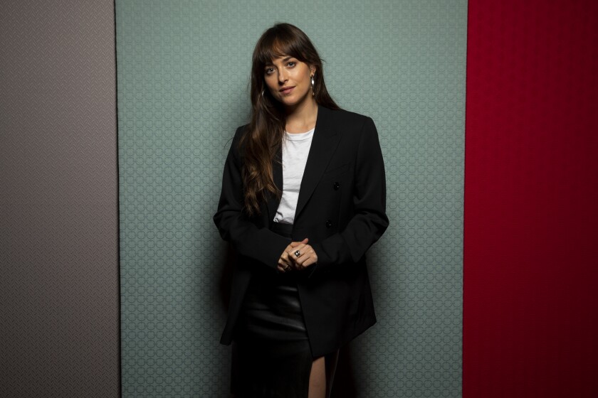 Dakota Johnson poses in a black skirt and blazer at the Toronto Film Festival