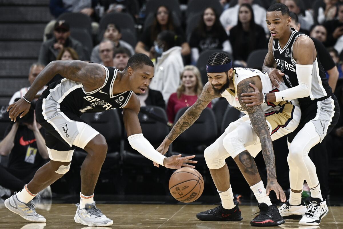 San Antonio Spurs' Lonnie Walker IV, left, and Dejounte Murray, right, fight for possession against New Orleans Pelicans' Brandon Ingram during the first half of an NBA basketball game, Sunday, Dec. 12, 2021, in San Antonio. (AP Photo/Darren Abate)