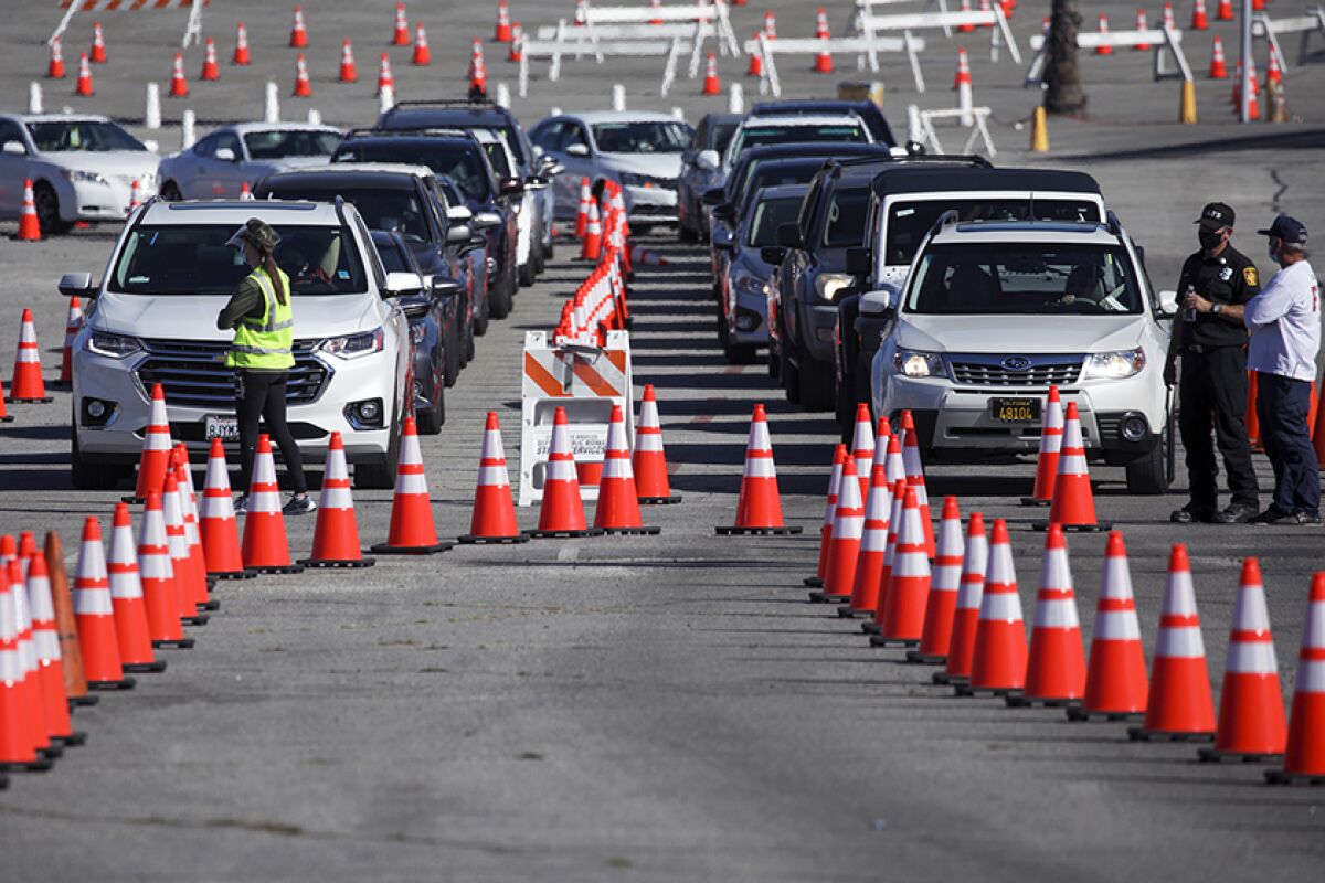 Drivers enter a mega COVID-19 vaccination site set up in the parking lot of Dodger Stadium.