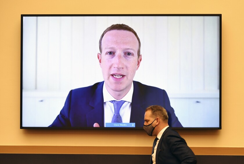 Facebook CEO Mark Zuckerberg is seen on a large screen mounted on a wall