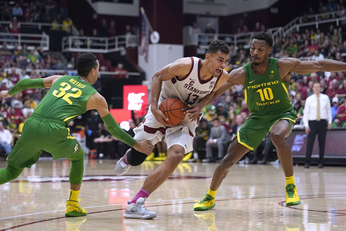 Stanford's Oscar da Silva, who had a career-high 27 points and added 15 rebounds, drives against Oregon's Anthony Mathis, left, and Shakur Juiston.