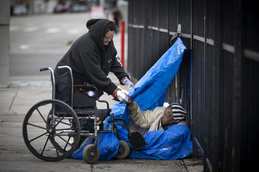 Sandra Bejarano, 45, left, shares food and water with Brenda Bryant, 60, right in the skid row in December. Bejarano said she recently lost housing. (Francine Orr / Los Angeles Times)