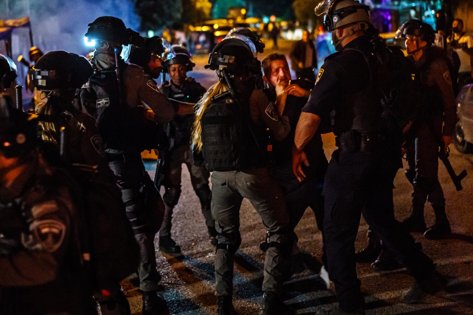 Police officers surround a man in the street.