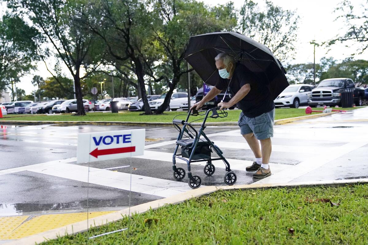 Franklin Castellon, de 76 años, se cubre de la lluvia mientras camina hacia una casilla para votación 