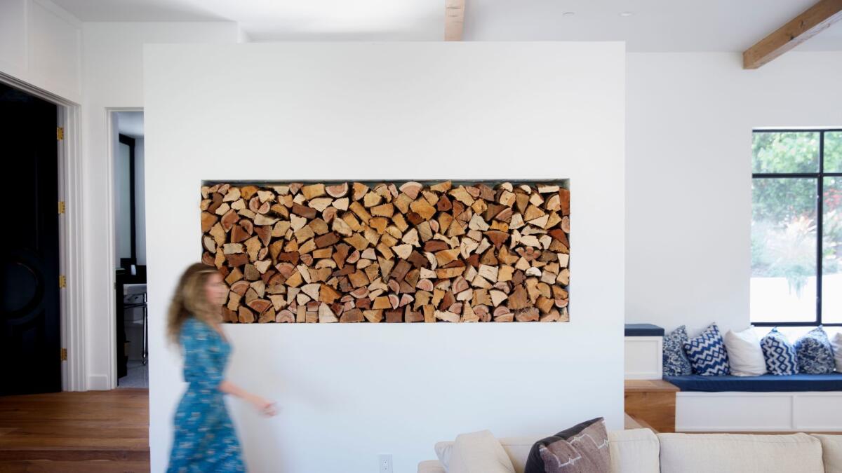 LOS ANGELES, CA--MAY 12, 2017--In the living room, firewood adds warmth and artistry to a white wall, with rustic wide plank oak floors and hand-scraped Douglas-fir ceiling beams, in the Studio City, CA., home of Jamie Klasfeld, photographed May 12, 2017. (Jay L. Clendenin / Los Angeles Times)