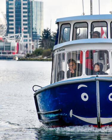 Vancouver's False Creek Ferry with father and son aboard, the Science World dome in background.