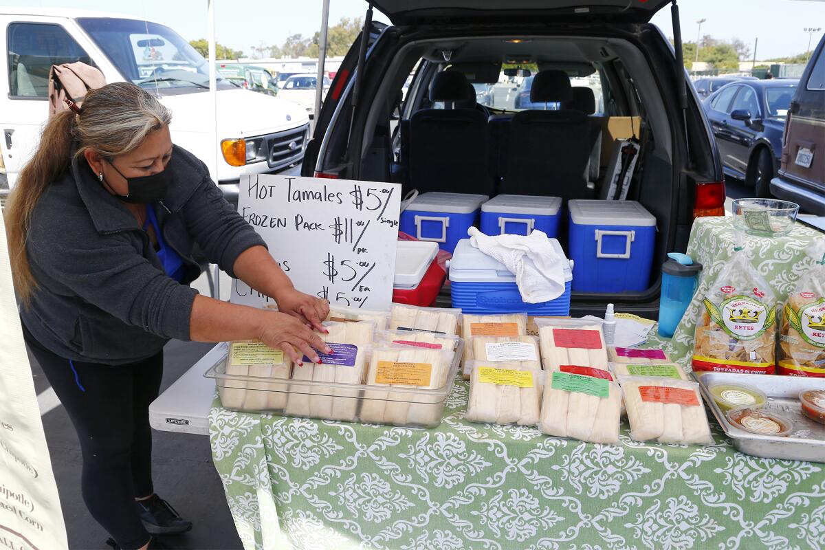 Leticia Manuel arranges a display of frozen gluten-free tamales during the Farmers Market Thursday at the O.C. fairgrounds.