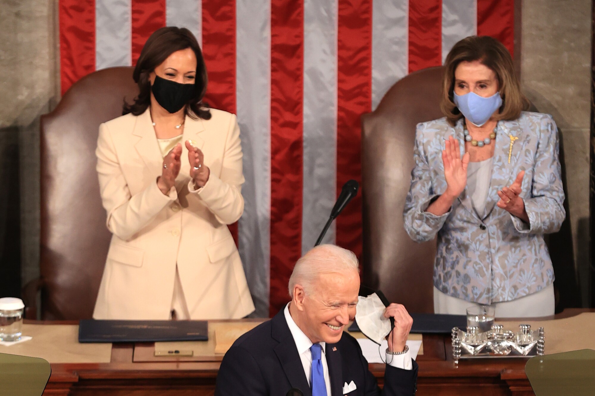 President Biden smiles as two women stand behind him.