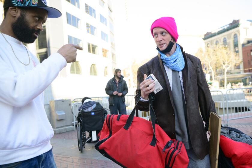 SAN FRANCISCO, CA - DECEMBER 17, 2022 - Avieira evans, of Health Right 360, passes out Narcan to a drug user at UN Plaza in San Francisco, California on December 17, 2022. Dozens of people consume fentanyl, meth and other illegal substances in public near the site of a recently closed safe consumption site. (Josh Edelson/for the Times)