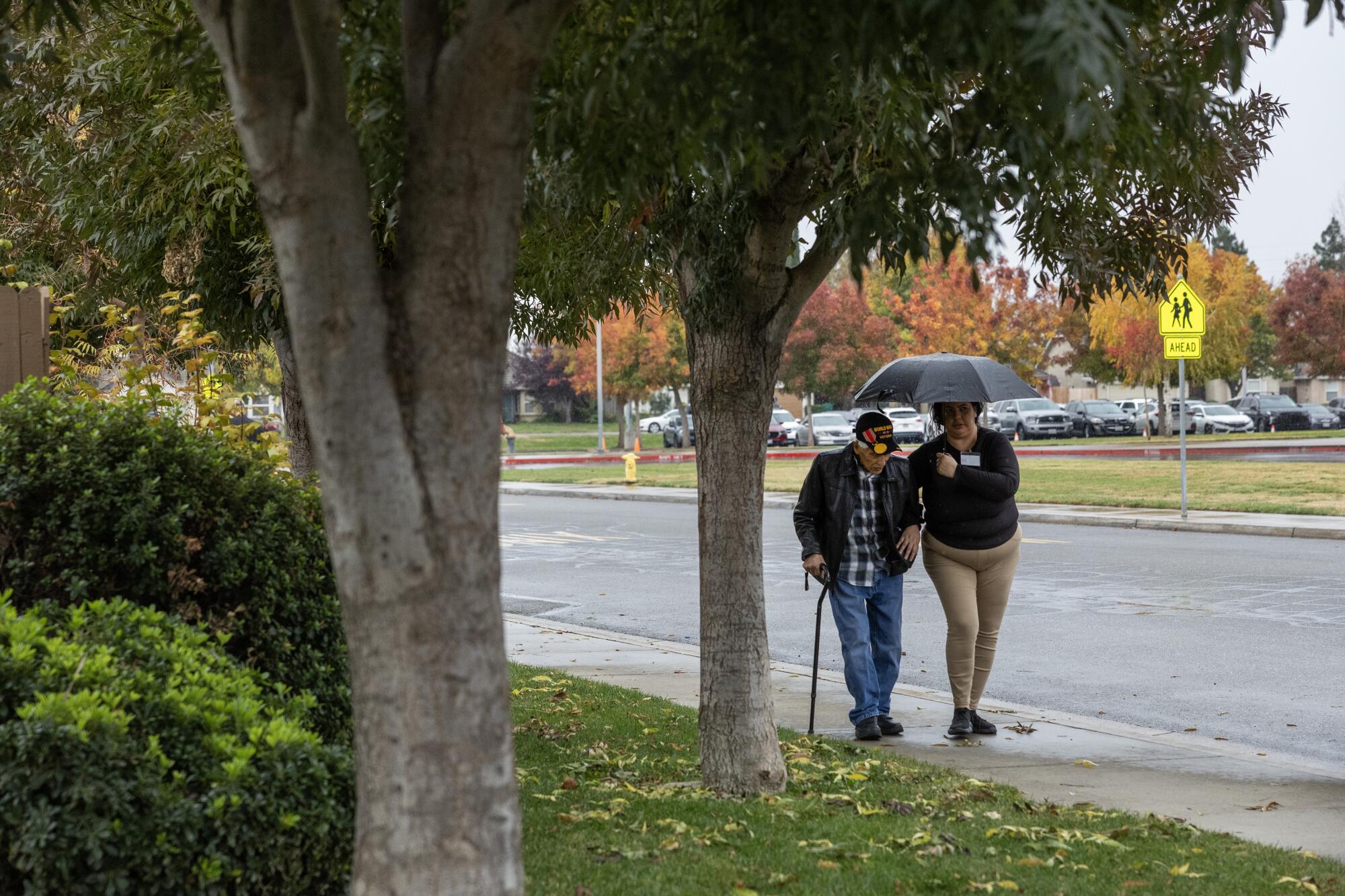 Bob Fernandez, 100, takes a morning walk with caretaker Maria Dominguez in Lodi, Calif.