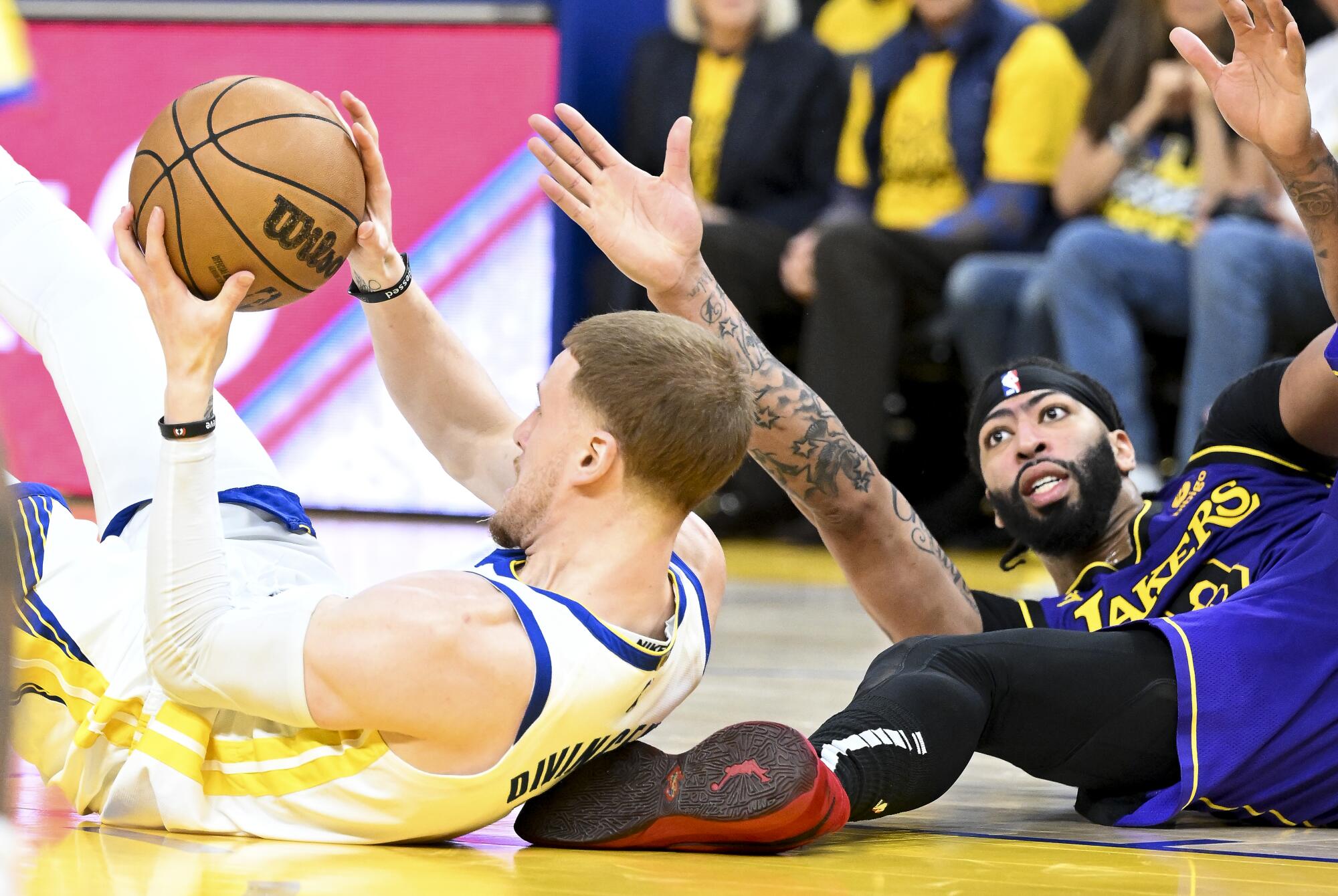 Golden State Warriors guard Donte DiVincenzo, left, grabs a loose ball in front of Lakers forward Anthony Davis.