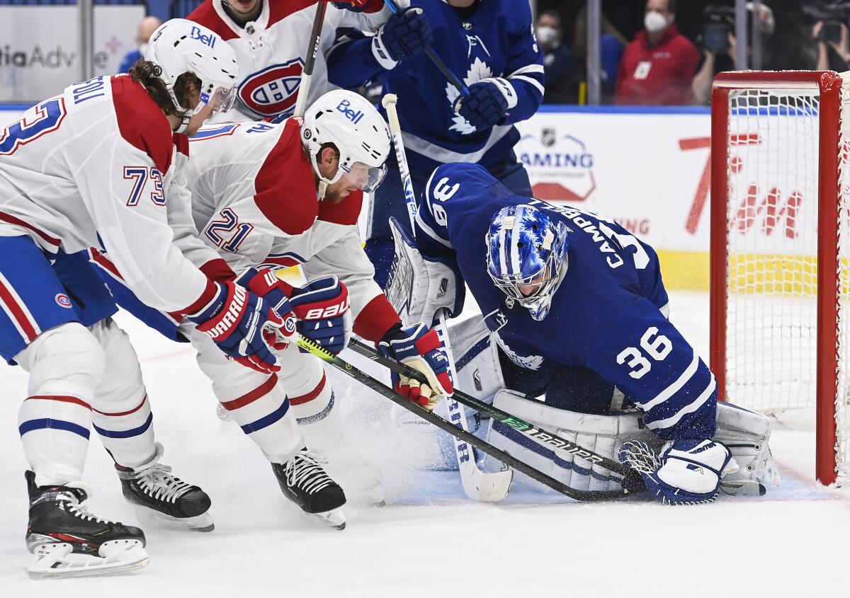Montreal Canadiens forward Eric Staal (21) and teammate Tyler Toffoli (73) poke at the covered puck under Toronto Maple Leafs goaltender Jack Campbell's glove during the second period of an NHL hockey game Wednesday, April 7, 2021, in Toronto. (Nathan Denette/The Canadian Press via AP)