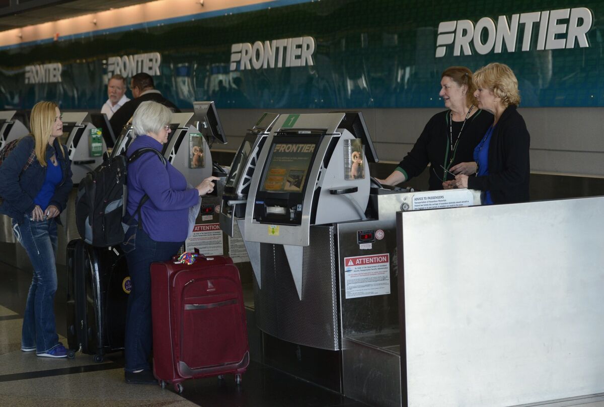 Frontier Airlines customer service agents help customers at the ticket counter at Denver International Jan. 16, 2015.