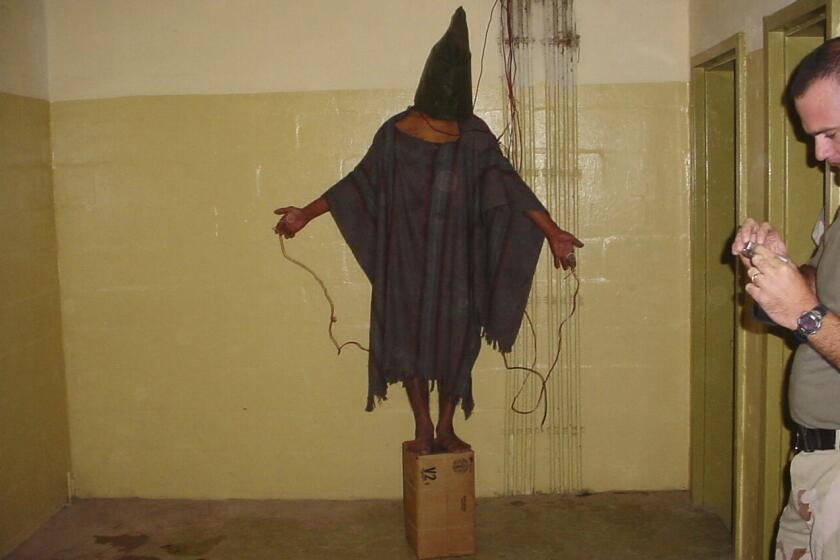 ARCHIVO - Esta imagen obtenida por The Associated Press muestra a un detenido no identificado de pie sobre una caja con una bolsa en la cabeza y cables atados a él en la prisión de Abu Ghraib en Bagdad, Irak, a finales de 2003. (AP Foto, Archivo)