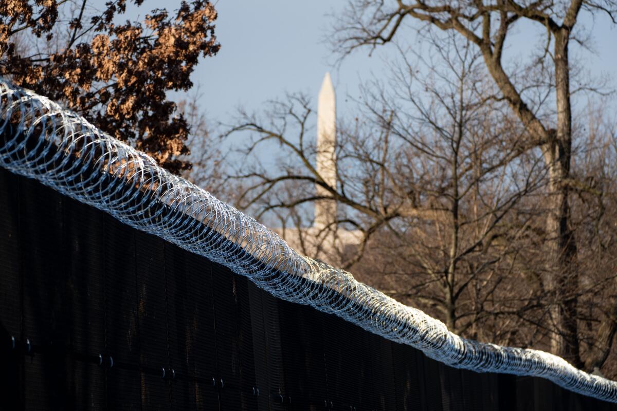 The Washington Monument is visible beyond barbed wire installed around the U.S. Capitol.