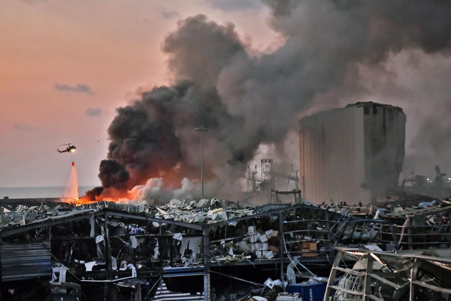 A helicopter puts out a fire at the scene of an explosion at the port of Lebanon's capital Beirut on August 4, 2020.