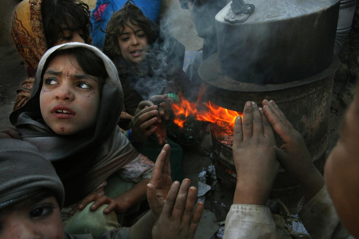 A file photo from 2012 show children warming themselves by a stove fueled by paper they collected around the camp. An estimated 30,000 to 40,000 internally displaced people had settled in informal settlements around Kabul in search of jobs and shelter.