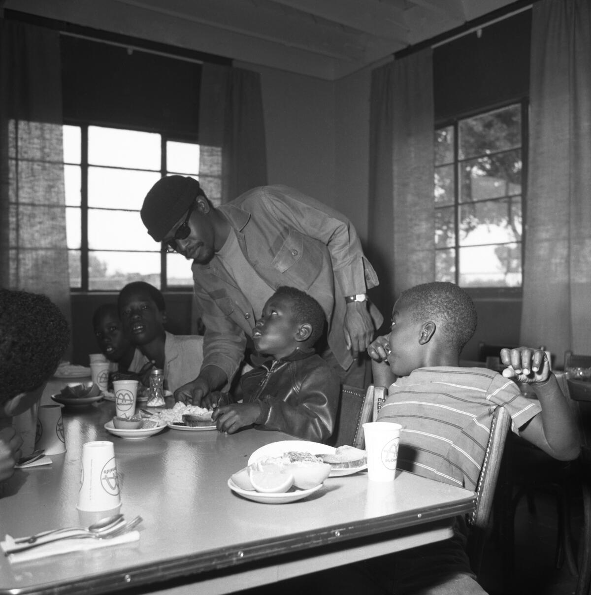 In 1969, a Black Panther in San Diego serves children as part of the party's free breakfast program