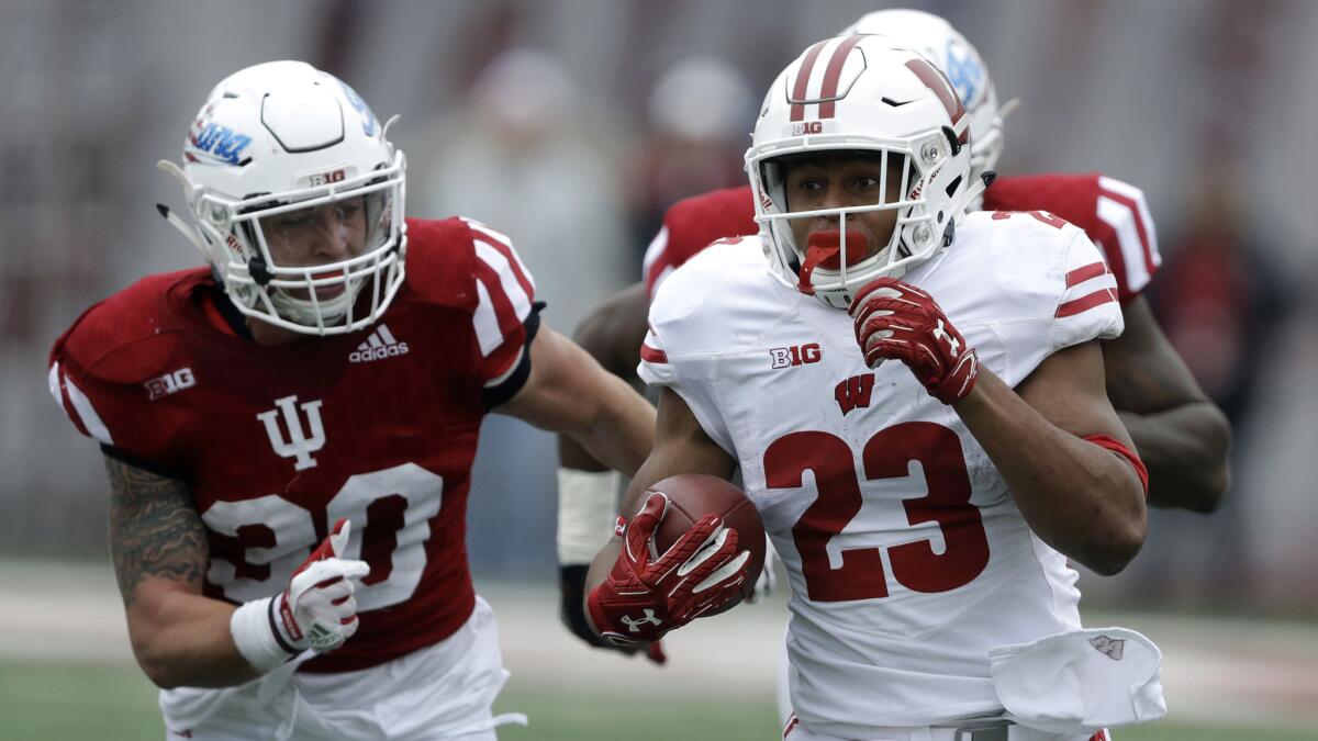 Wisconsin's Jonathan Taylor (23) breaks into the Indiana secondary past safety Chase Dutra during the first half Saturday.
