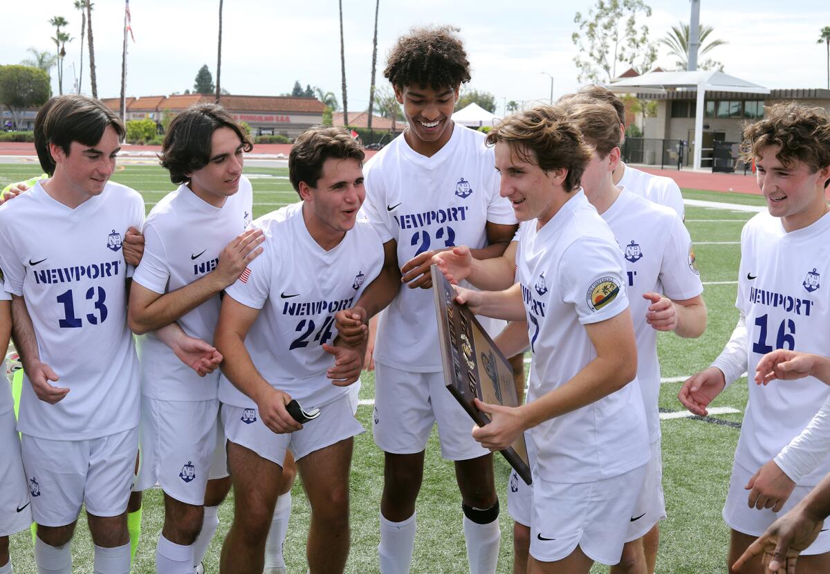 Newport Harbor boys' soccer players celebrate with the championship plaque after beating Foothill on Saturday.