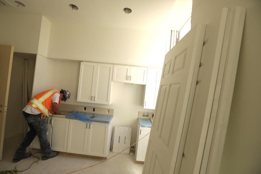 LOS ANGELES, CA - JUNE 23, 2022 - - A construction worker sands a kitchen counter inside a unit of Building 207 that is being refurbished as housing for veterans on the Veteran Affairs West LA campus in Los Angeles on June 23, 2022. This is the Collective's first project, a 60-unit building for senior veterans and their families and is scheduled to open this fall. Along with U.S. VETS, the Collective is made up of Century Housing, a nonprofit that builds and finances affordable housing, and Thomas Saffran and Associates, a Brentwood-based for-profit affordable housing developer. The master plan calls for 14 buildings to be brought up to current standards but preserved in their original form with another 14 built from the ground up. (Genaro Molina / Los Angeles Times)