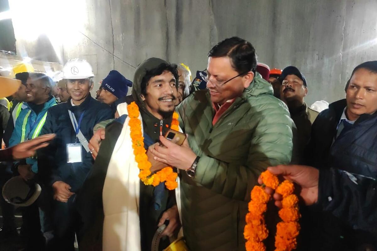 An Indian state official greets a rescued worker with a garland around his neck.