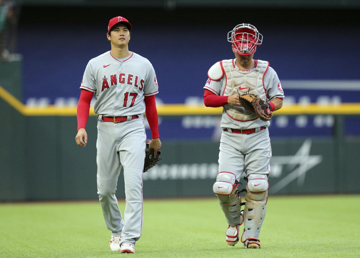 Angels starting pitcher Shohei Ohtani and catcher Kurt Suzuki walk to the dugout.