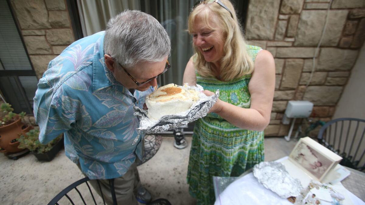 Mary Caldwell laughs as her husband, Alan, smells their wedding cake, still frozen since they got married 50 years ago.