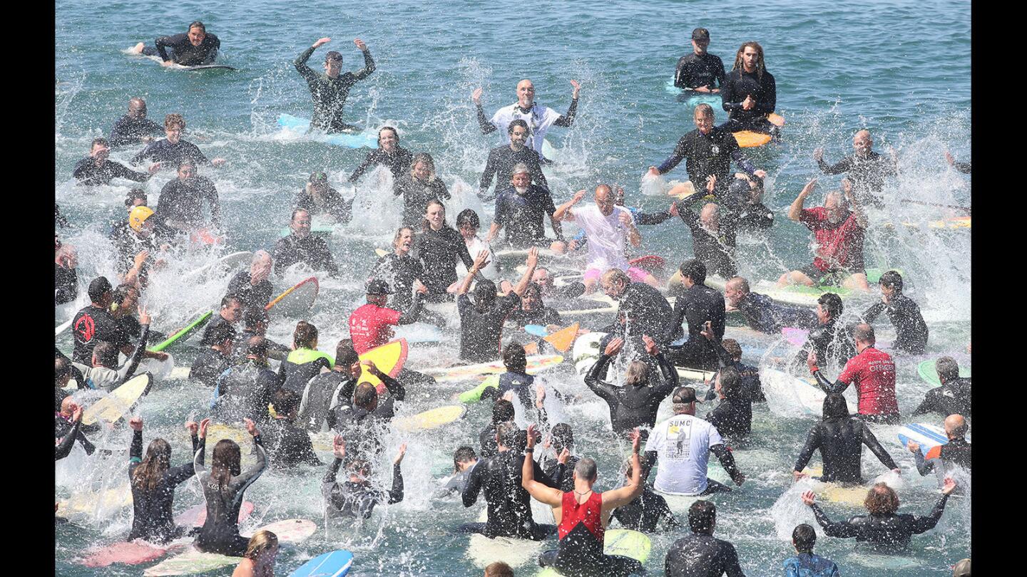 Hundreds of friends and family splash their hands and throw water in honor of Blaine "Sumo" Sato during his memorial paddle-out ceremony on the north side of the Huntington Beach Pier on Saturday.