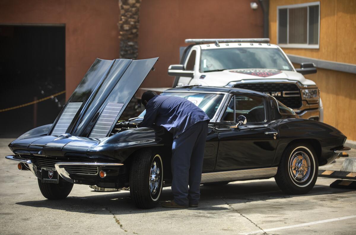 A worker attends to a 1960s Chevrolet Corvette at Beverly Hills Car Club.