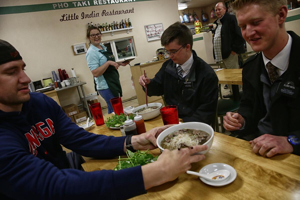 Brittney Stirling serves Pho to Mormon missionaries at the Pho Taki Little India Restaurant.