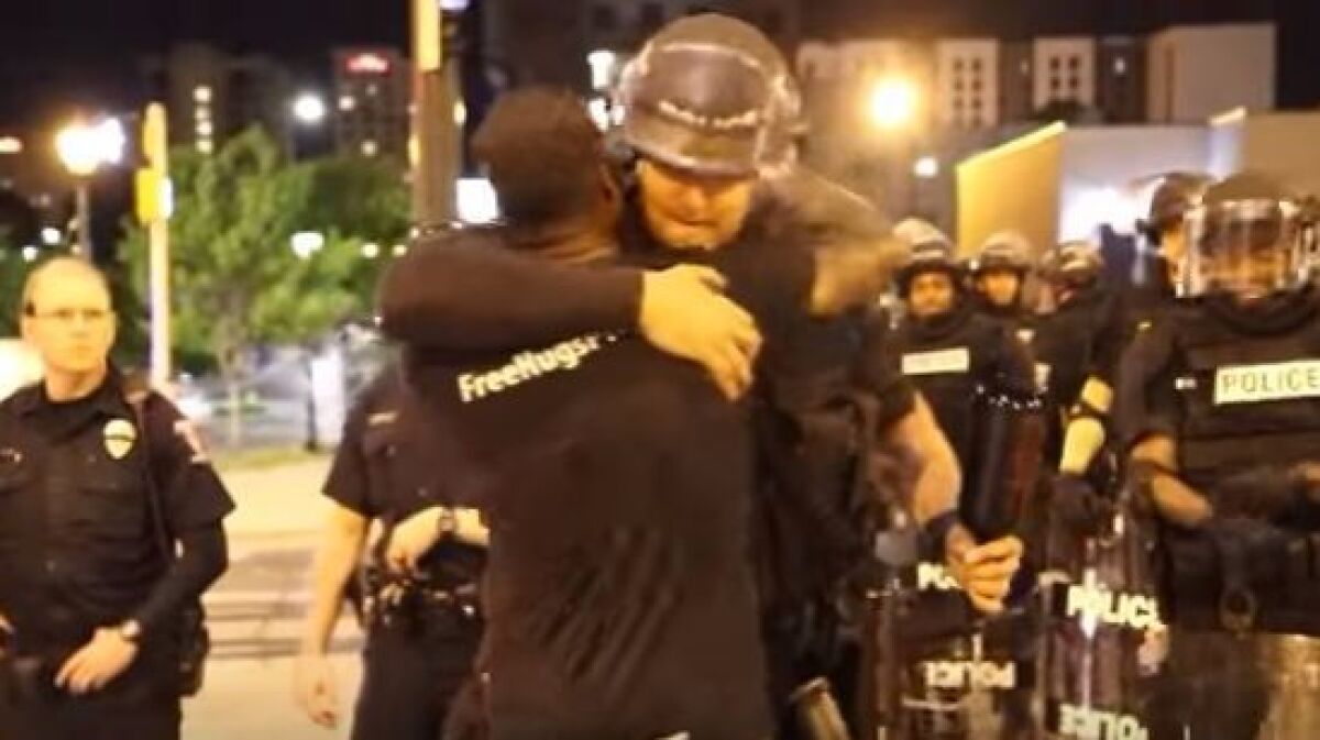 Ken Nwadike Jr. is seen in this screen grab from a YouTube video hugging police officers during a night of unrest in North Carolina in 2016.
