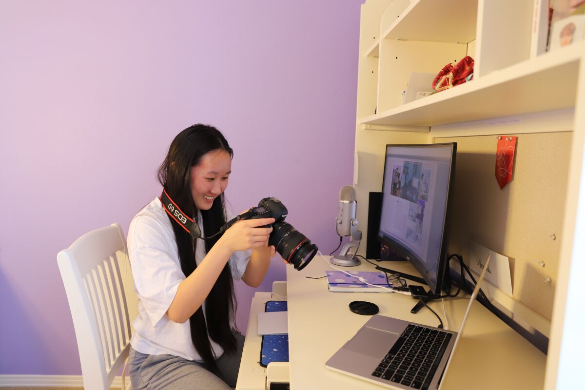 Amanda Zhang, yearbook editor at Canyon Crest Academy, looks at photos in her home office in Carmel Valley.