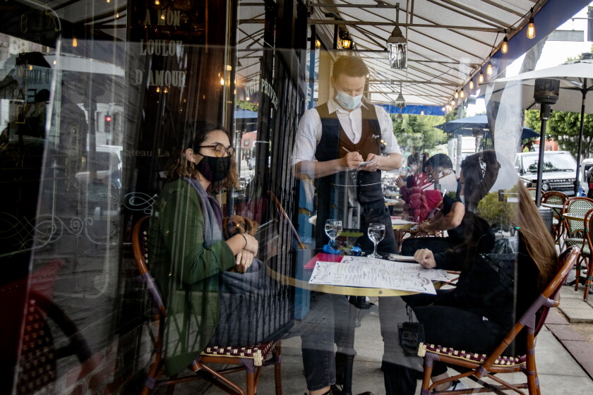 California reopening: Why officials say it's safer this time
around 3 LOS ANGELES, CA - MARCH 15, 2021: Waiter Boris Macquin serves customers behind plexiglass outside at Figaro Bistro on the first day Los Angeles County allows indoor seating since the coronavirus pandemic on March 15, 2021 in Los Angeles, California. Many customers didn't realize indoor seating was allowed. The restaurant spread out the indoor seating and installed plexiglass at each table.(Gina Ferazzi / Los Angeles Times)
