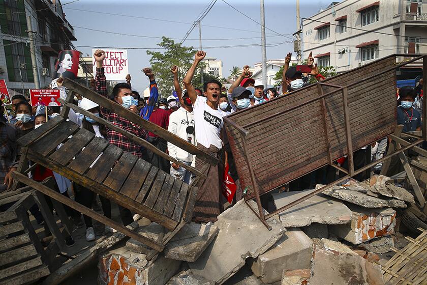 Anti-coup protesters shout slogans behind makeshift barriers in Mandalay, Myanmar, on Sunday.