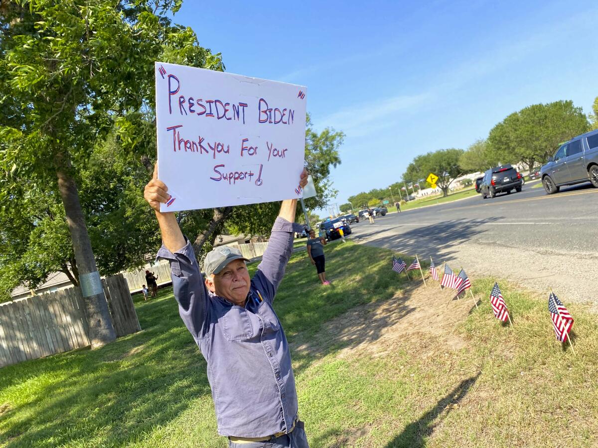 A man holds a sign reading, "President Biden thank you for your support."