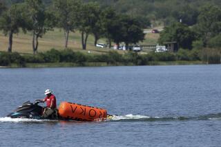 A jet ski pulls in buoys from the CrossFit Games at Marine Creek Lake, where an athlete drowned during the run swim event on Thursday, Aug. 8, 2024 in Fort Worth, Texas, (Amanda McCoy/Star-Telegram via AP)