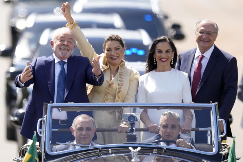 El presidente electo Luiz Inácio Lula da Silva, izquierda, su esposa Rosangela Silva, segunda de izquierda a derecha, el vicepresidente electo Geraldo Alckmin, derecha, y su esposa María Lucía Ribeiro avanzan en un automóvil descapotado para la ceremonia de investidura de Lula, el domingo 1 de enero de 2023, en Brasilia, Brasil. (AP Foto/André Penner)