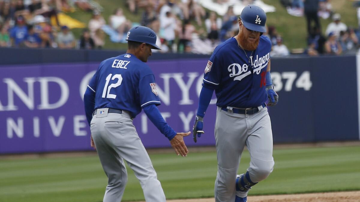 The Dodgers' Justin Turner, shown here Thursday with third base coach Dino Ebel, has been swinging a hot bat in spring training.
