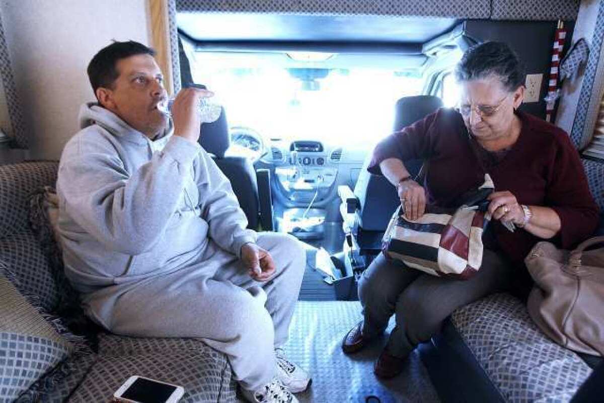 Ara Manoogian takes a drink of water with his mom, Sylva Manoogian, in his RV on Monday.